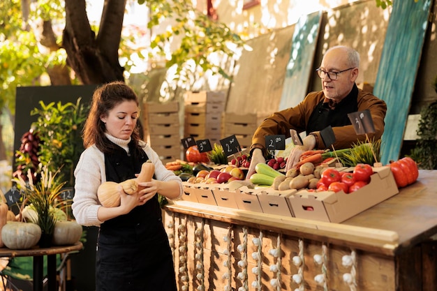 Lokale standverkopers beginnen de dag met verse natuurlijke producten en werken bij een marktkraam om gezonde producten te verkopen. Jonge vrouw die groenten en fruit op de boerenmarkt zet.