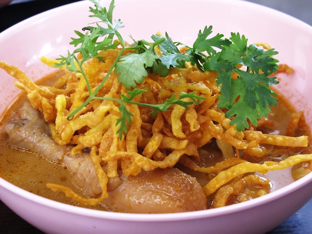 Lokale traditionele Thaise gerechten khao soi gai of keuken Noord-Thaise curry soep noedels met kip serveren groente bijgerecht op keramische schotel plaat bij lokale restaurant winkel in Chiang Rai Thailand