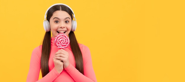 헤드폰을 끼고 있는 롤리팝 아이 아이는 스틱 캐러멜 사탕 가게에 사탕 설탕 사탕을 들고 있습니다 과자 포스터 배너 헤더 복사 공간이 있는 십대 어린이