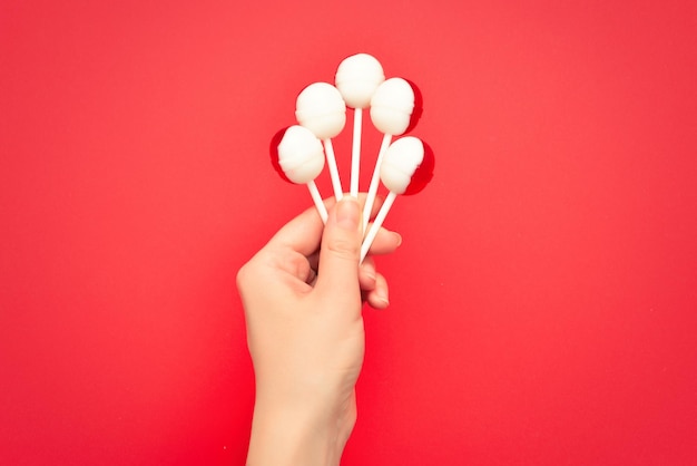 Lollipop in female hand on red background Space for text or design