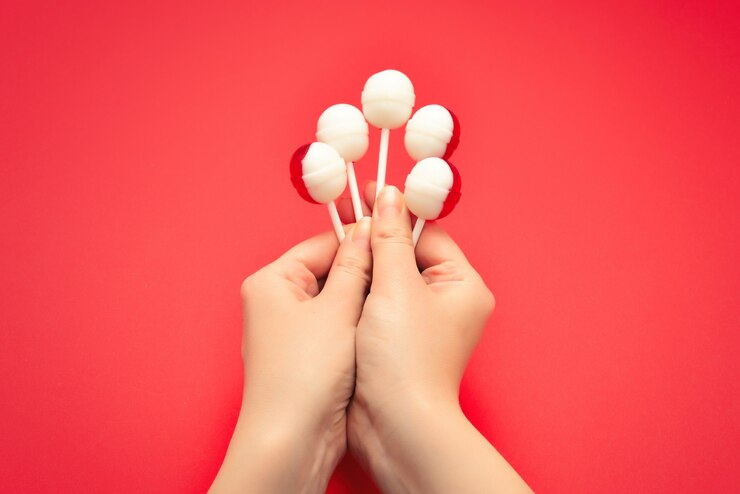 Photo lollipop in female hand on red background. space for text or design.