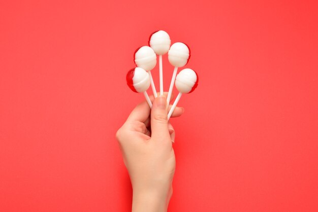 Lollipop in female hand on red wall