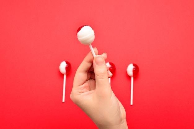 Lollipop in female hand on red