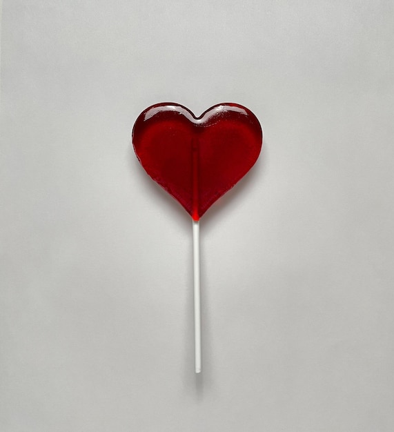 Lollipop in the shape of heart on white background. Copy space, top view.