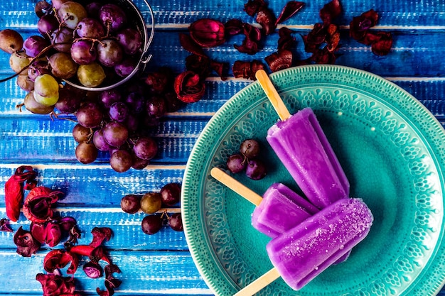 A Lollipop style grape ice cream on a stick on a vintage plate on a light blue wooden table Concept of natural and healthy eating Copyspace