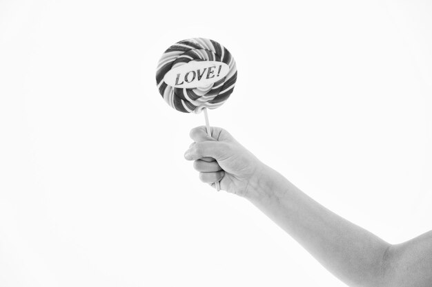 Photo lollipop with love lettering isolated on white candy on stick in hand sweet candy swirl valentines day concept food and dessert eating copy space lollipop fun
