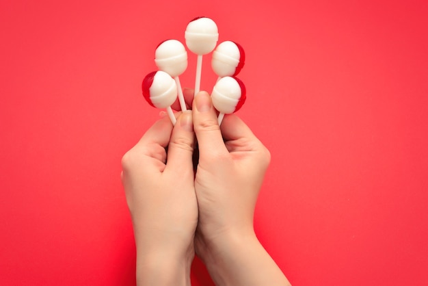 Lolly in vrouwelijke hand op rode achtergrond