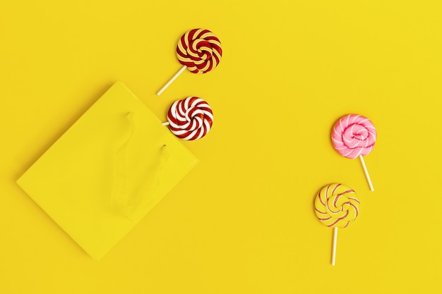 Lollypop sweet caramel candy on stick  yellow paper bag