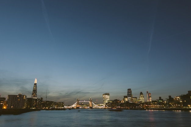 Photo london skyline at dusk with river thames on foreground