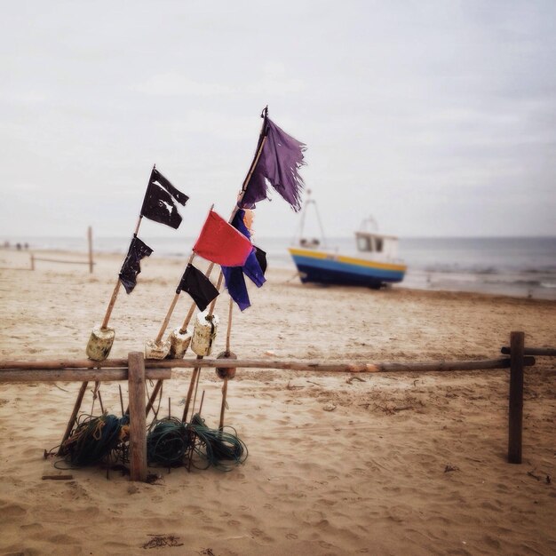 Lone boat on calm beach with flags in foreground