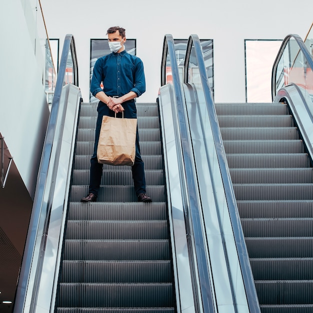 Lone man in a protective mask standing on the escalator steps . photo with a copy-space