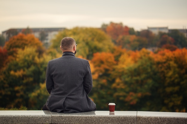 一人の男が石のベンチに座っていると自然を見ています。