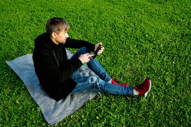写真 孤独な、一人で、公園でコーヒーを飲む一人の中年男性。孤独、社会的距離、自己嫌悪の概念。自然とつながるメンタルヘルスのコンセプト