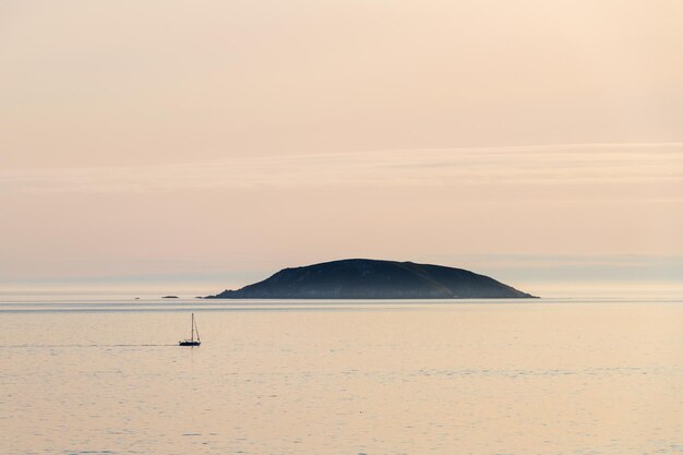 Foto una barca solitaria naviga vicino all'isola di onza nella ria de pontevedra in galizia durante il tramonto