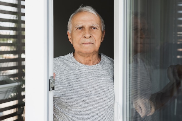 Lonely elderly man looking into the window