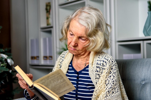 Lonely elderly woman reading a book at home for christmas