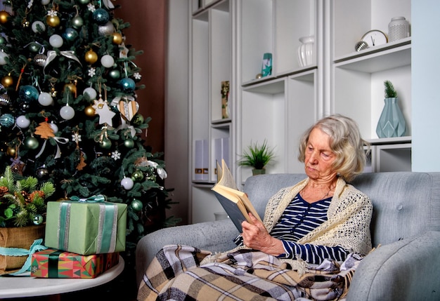 Photo lonely elderly woman reading a book at home for christmas.