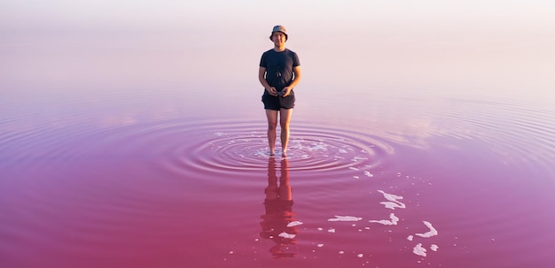 巨大なピンク色の湖を背景に孤独な男の姿
