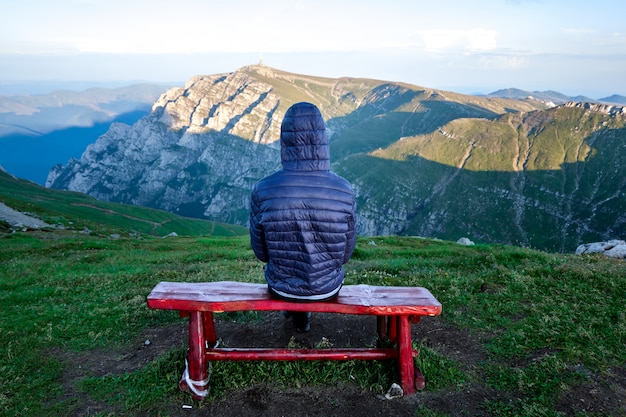 Lonely hiker man sitting on red chair on top of Bucegi mountains