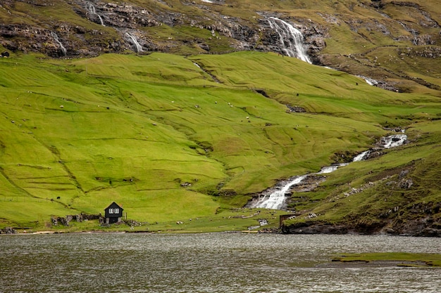 Одинокий дом и водопады в районе саксун на фарерских островах