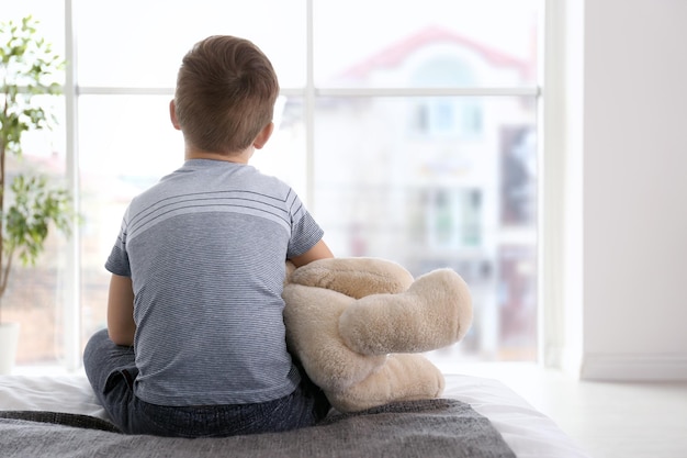 Lonely little boy sitting on bed in room Autism concept