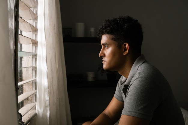 Photo lonely man looking and thinking in front of a window concept mental health and masculine crisis