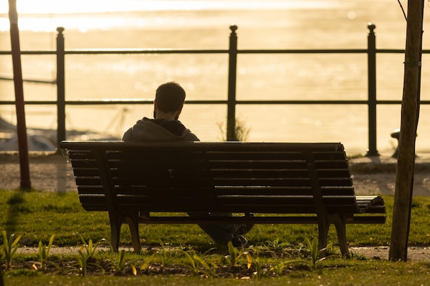 Lonely man sitting on a bench at early sunset