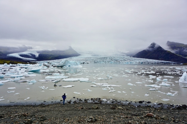 孤独な男は、アイスランドのFjallsarlon氷河の岸にある無限を凝視します。