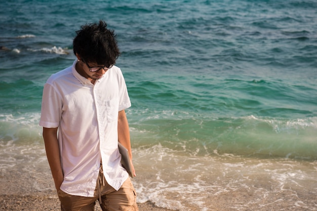 사진 컴퓨터 노트북과 외로운 남자는 바다에서 해변을 걷고있다.