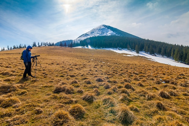 Lonely photographer in mountains with a camera on a tripod in cold weather