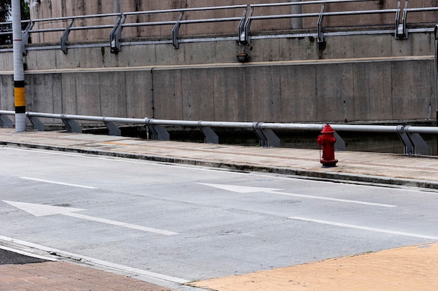 Одинокий красный пожарный гидрант выделяется среди серой и промышленной среды Медельина, Колумбия.
