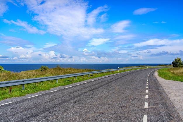 Lonely road by the sea heading nowhere, with cloudy skies.