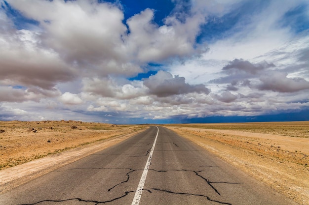 Foto strada solitaria nel deserto sotto un cielo nuvoloso