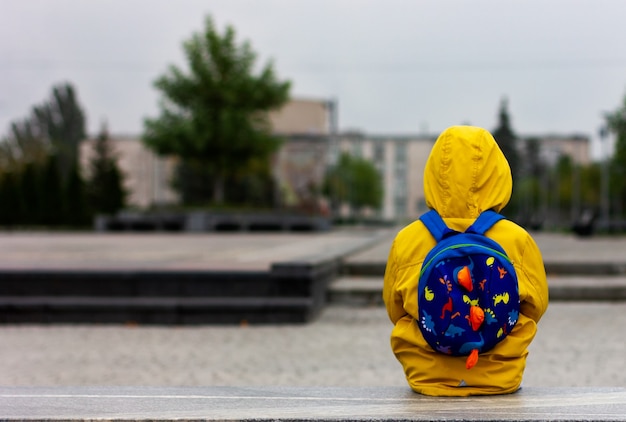 A lonely sad boy in an empty city isolation pandemic quarantine thinking alone boy in a yellow raincoat