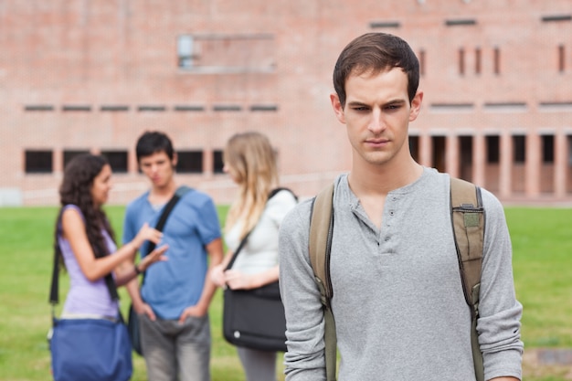 Lonely student posing while his classmates are talking