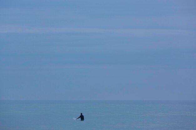 Lonely surfer on flat Pacific Ocean waiting for the wave Mancora