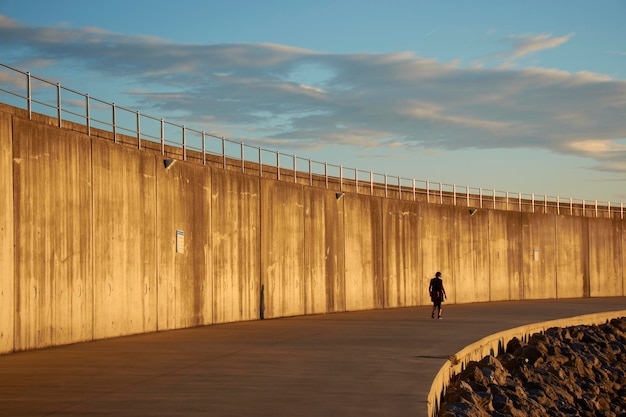 Lonely walker at sunrise on concrete walkway