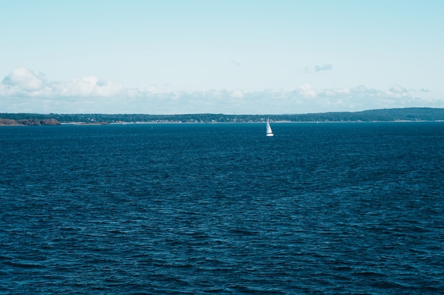 Lonely white Sailboat sailing on peaceful and calm water of Moss