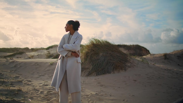 Lonely woman admiring beach dunes black hair model get cold resting seaside