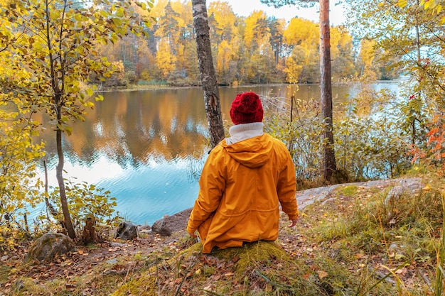 La donna sola è seduta sulla riva di un lago forestale