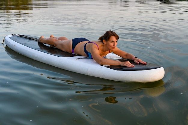 A lonely woman lies on Sup Bord surrounded by a lake at sunset Lake Lebyazhye Kazan Active weekend vacations wild nature outdoor