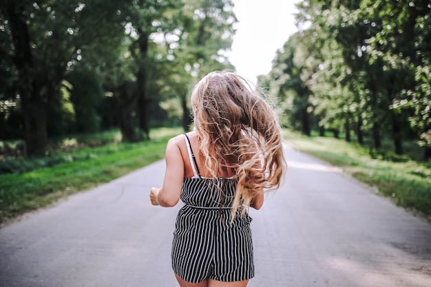 Photo lonely woman walks along the road among the forest to meet new life in the summer