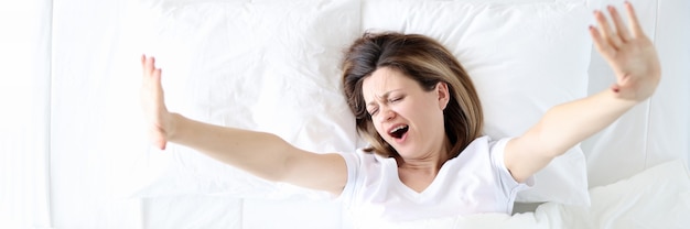 Одинокая женщина зевает и потягивается в постельном режиме и расслаблении после концепции рабочего дня