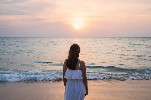 Lonely young asian woman standing on the beach at sunset