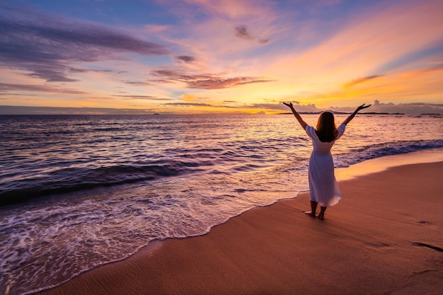 Giovane donna sola che cammina e si gode il bellissimo tramonto sulla spiaggia tranquilla viaggia in vacanza estiva