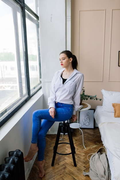 Lonely young woman in a white shirt at home