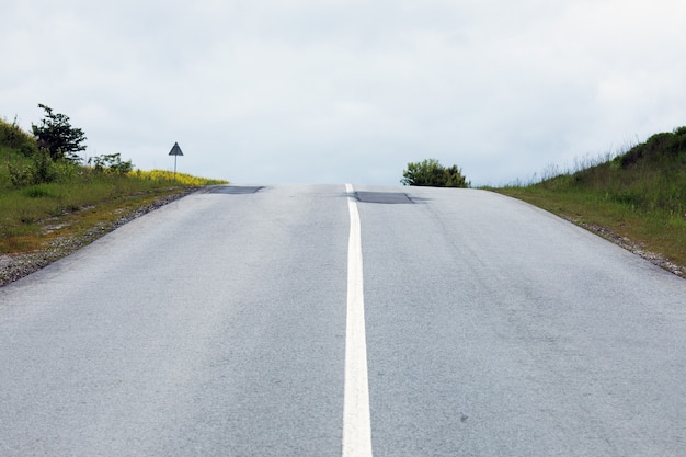 Long asphalt road with a white strip