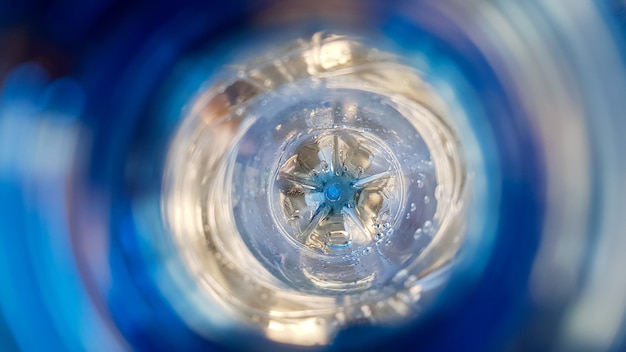 Long background with a plastic blue bottle with water drops inside.