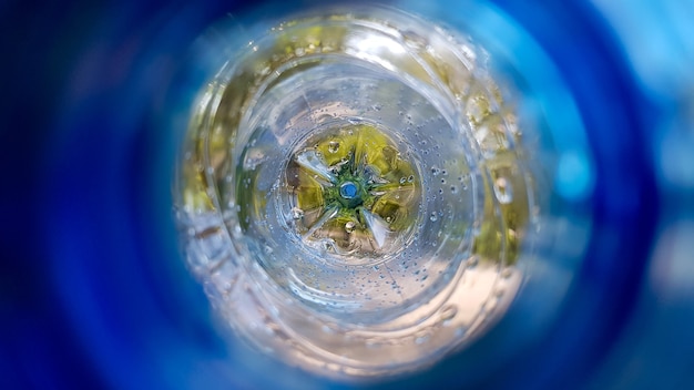 Foto sfondo lungo con una bottiglia di plastica blu con gocce d'acqua all'interno.