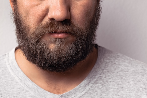 Barba lunga e baffi di un bell'uomo con la barba ritratto di un uomo con la barba in maglietta grigia